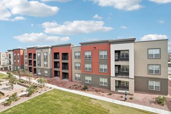 an apartment building with a green lawn and a blue sky at The Maddox Luxury Apartment Homes, Arizona, 85326